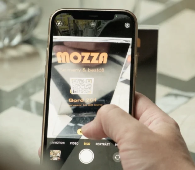 Gäst skannar en QR-kod på bordet med sin smartphone för att beställa